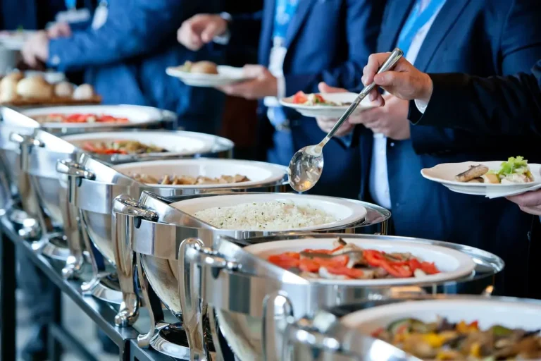 Pessoas se servindo em um buffet, representando o que é intervalo Intrajornada.
