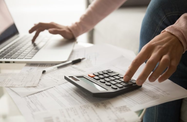 calculo de custo do funcionario, imagem mostra uma pessoa usando o notebook e calculadora ao mesmo tempo.