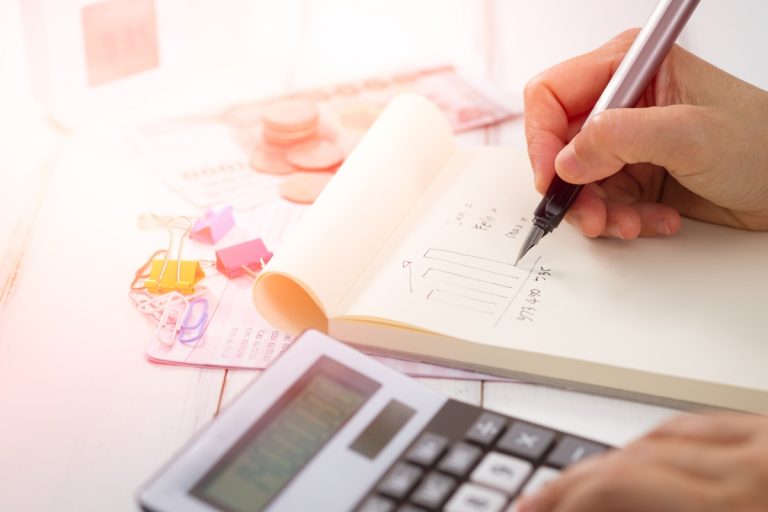 Uma pessoa está com caneta em mãos e uma calculadora para fazer cálculos e gráficos da taxa de absenteísmo