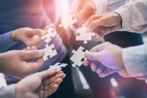 Imagem ilustra uma equipe juntando as peças, mostrando como o trabalho em equipe de uma equipe de alto desempenho pode ser feito