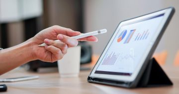 Profissional analisando dados de de people analitycs em tablet. Tangerino agora é Sólides