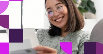 Mulher jovem de óculos e suéter verde sorri enquanto analisa um documento impresso de folha de pagamento. O arquivo gráfico conta com elementos geométricos roxos e a marca da Sólides.