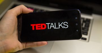 Foto de uma mão segurando um celular, onde é possível ler o TED Talks