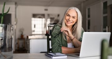 Mulher com autonomia no trabalho sorrindo sentada em frente a notebook