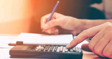 imagem de uma pessoas escrevendo e calculando, simulando o calculo de salário.