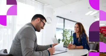 Um recrutador sorridente analisando documentos em uma mesa redonda enquanto entrevista uma candidata em um ambiente de escritório iluminado. A imagem contém elementos gráficos em tons de roxo e rosa e o logotipo da Sólides no canto inferior esquerdo, ilustrando agilidade e tecnologia no recrutamento e seleção.