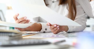mãos femininas segurando um papel representando a análise de um currículo