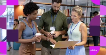 Três profissionais de Recursos Humanos em pé em um escritório moderno, usando crachás e analisando juntos documentos em uma pasta amarela, representando a gestão e planejamento de férias compulsórias na empresa.