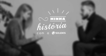 foto preto e branca, com efeito embaçado, um homem e uma mulher sentados de frente um para o outro, a mulher com um bloco de anotações na mão
