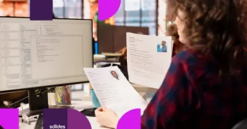 Recrutador analisando currículos impressos em um escritório para aplicar a estratégia de recrutamento às cegas.