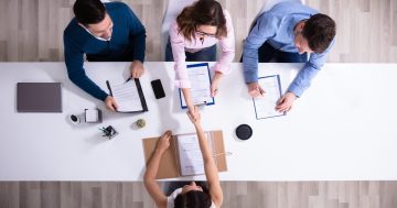 três pessoas em frente a uma mesa realizando uma seleção por competências em frente a uma pessoa