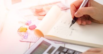 Uma pessoa está com caneta em mãos e uma calculadora para fazer cálculos e gráficos da taxa de absenteísmo